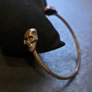 Vintage brass or copper-toned cuff bracelet featuring intricately detailed skull